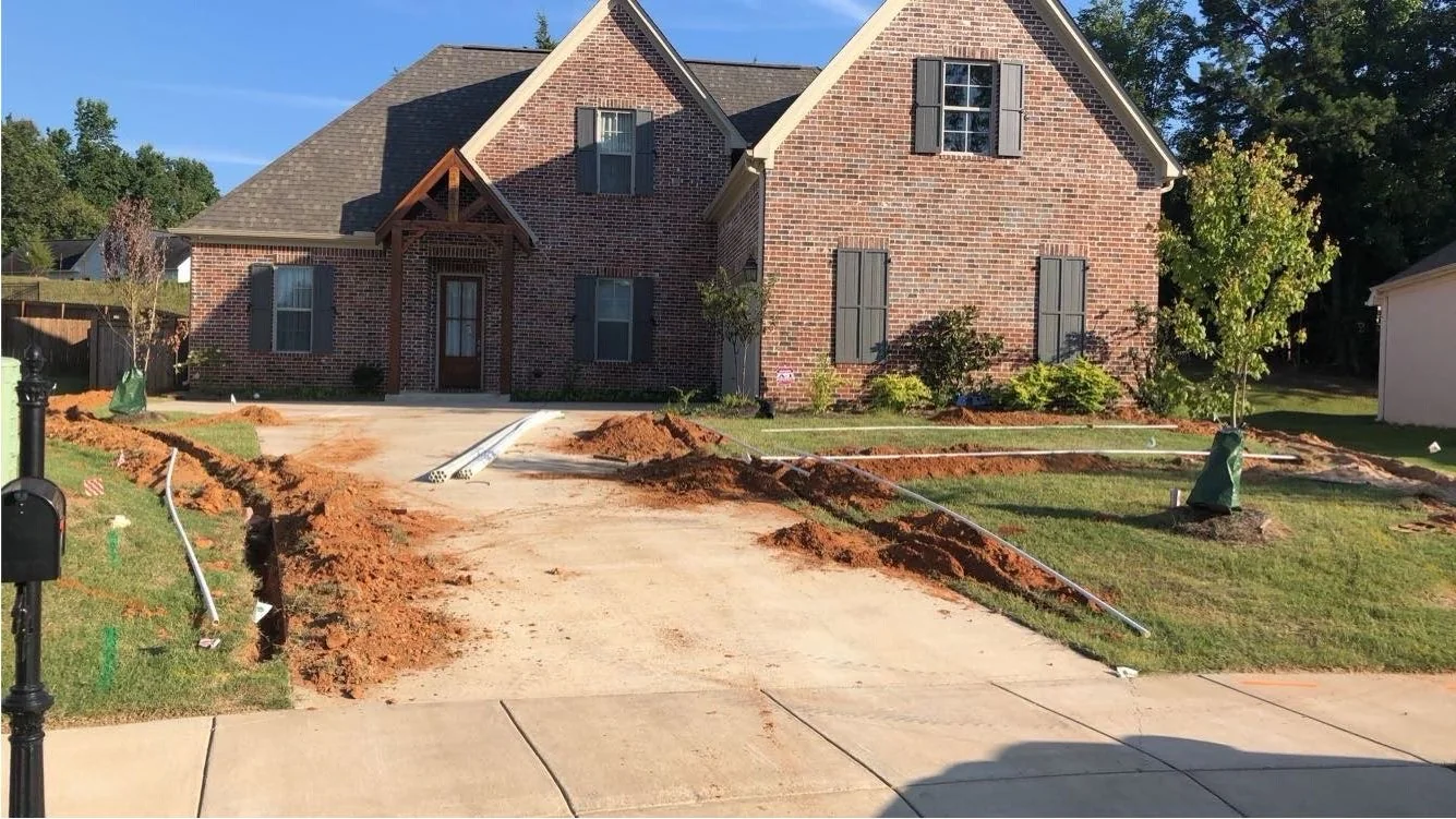 Irrigation system installation in progress at a new-build home in Oxford MS, trench cut along the driveway by Oxford Lawn Pro